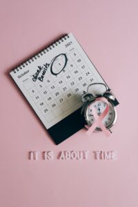 Pink ribbon with alarm clock and calendar promotes breast cancer awareness in October.